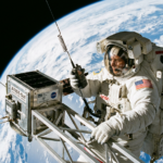 An astronaut in space holding a walkie talkie